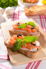 Delicious bruschetta with tomatoes on cutting board close-up