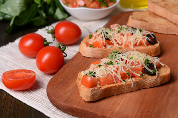 Delicious bruschetta with tomatoes on cutting board close-up