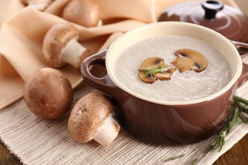 Mushroom soup in pot, on wooden background