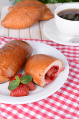 Fresh baked pasties with strawberries on plate on table