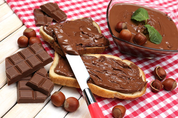 Bread with sweet chocolate hazelnut spread on wooden background