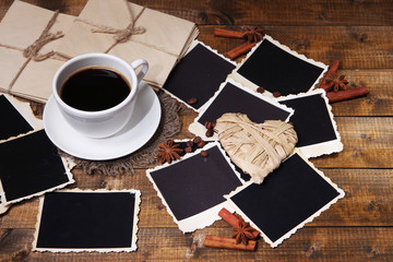 Fototapeta na wymiar Filiżanka kawy i stare puste zdjęcia na tle drewniane