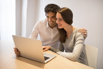 Cheerful couple surfing the net and Using Laptop At Home