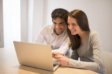 Obraz na płótnie Canvas Couple using credit card to shop on line. Laptop. Indoor desk