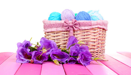 Fototapeta na wymiar Purple artificial eustoma and woolen balls of yarn in basket