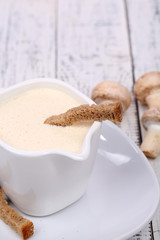 Delicate mushroom sauce in pitcher on wooden table close-up
