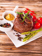Delicious beef steaks with fresh vegetable and trimmings on wood