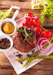 Delicious beef steaks with fresh vegetable and trimmings on wood