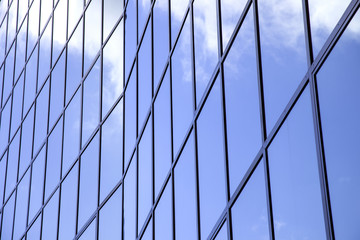 reflexions of clouds and blue sky in facade of modern building