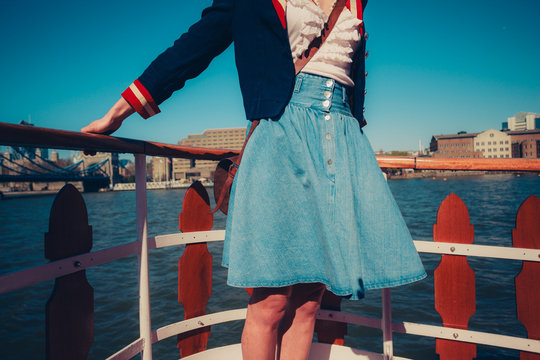 Young woman on the deck of ship with skirt blowing in the wind