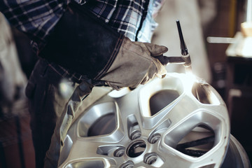 Alloy wheel repair, closeup of mechanic welding rim - obrazy, fototapety, plakaty