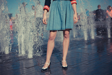 Young woman standing by fountain in city on a hot day