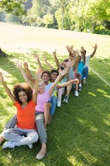 Row of friends raising hands in park