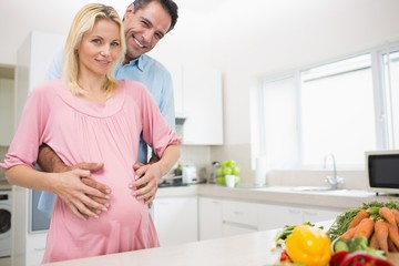 Portrait of a happy father with pregnant mother in kitchen