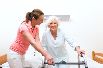 Pflegerin Tochter mit Seniorin und Gehbank