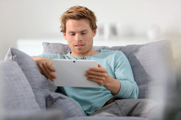 Portrait of young adult man in sofa with tablet