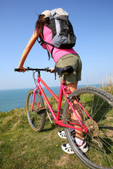 Young woman riding bike by ocean coast