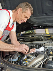 Car mechanic changes the oil of the engine