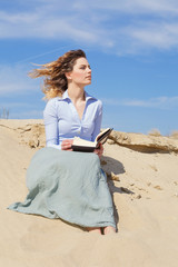 Beautiful wind hair woman reading a book on the beach