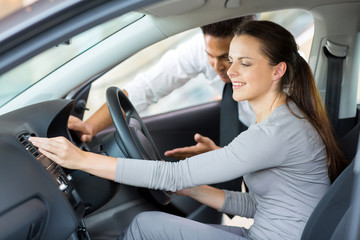 car sales consultant showing a new car to a young woman
