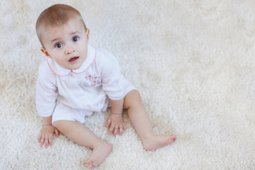 portrait of pretty smiling baby girl sitting on the floor