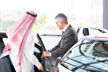 Arabian man getting in a new car for test drive