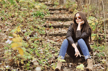Naklejka na ściany i meble Fashion girl sitting in a park wearing sunglasses