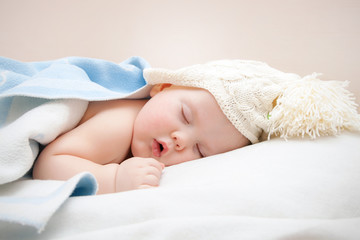 Cute sleeping baby in knitted hat with pompom