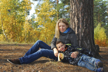 Mother and son in autumn forest.