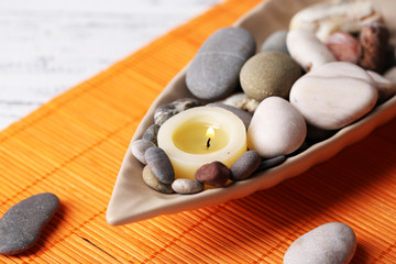 Fototapeta na wymiar Composition with spa stones, candles on bamboo mat background