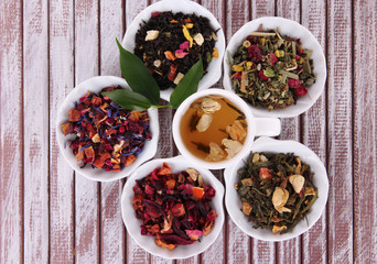 Cup of tea with aromatic dry tea in bowls on wooden background