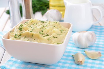 Delicious mashed potatoes with greens in bowl on table close-up