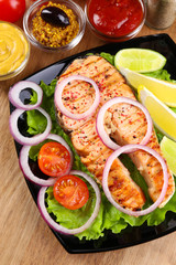 Tasty grilled salmon with lemon and vegetables, on wooden table
