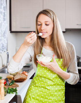 woman in apron eating curd cheese
