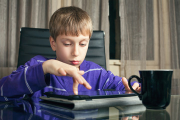 Fototapeta na wymiar Cute stylish funny boy playing at tablet computer