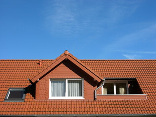 Ziegeldach mit Mansarde und Dachterrasse vor blauem Himmel bei Sonnenschein in Oerlinghausen bei...