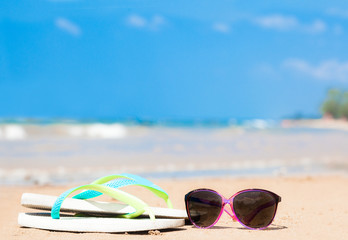 flip flops and sunglasses on tropical beach with waves on