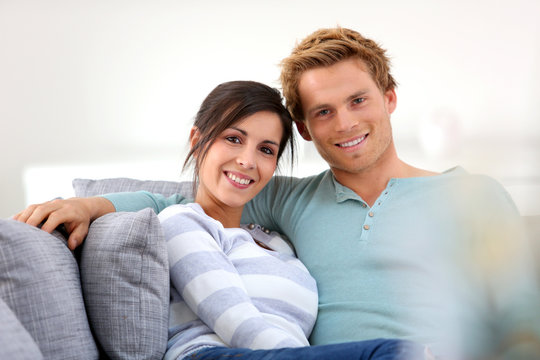 Cheerful young couple relaxing in sofa
