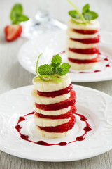Dessert of strawberries and bananas with fruit sauce.