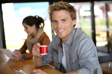 Young man in coffee shop wonnected on smartphone