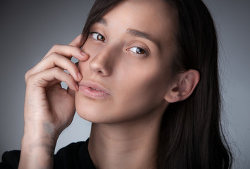 Closeup portrait of slim brunette woman holding hand near mouth