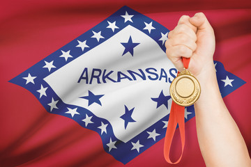 Medal in hand with flag on background - State of Arkansas.