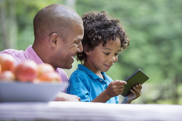 A picnic on the farm. Fresh organic fruit on the table. A father and son sitting together.