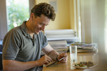 A person sitting alone in a cafe. A  man using a digital tablet.