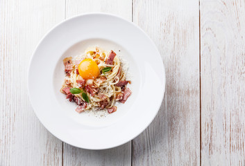 Spaghetti Carbonara on white plate with ham and yolk