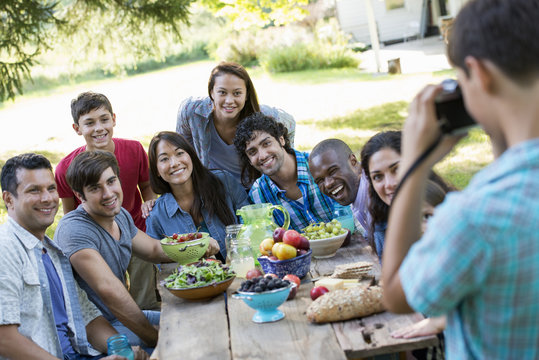 A summer party outdoors. Adults and children posing for a photograph.