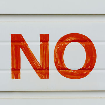 A large NO sign in red paint on a garage door, indicating No Parking. 
