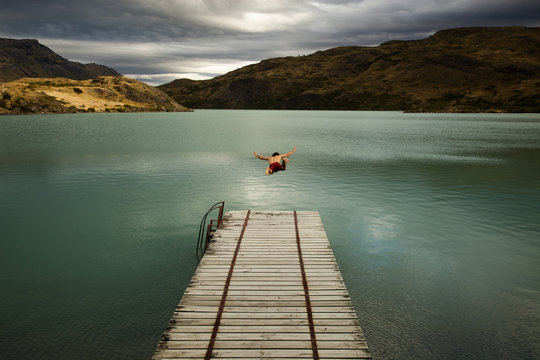 Man diving off pier into lake in Torres del Paine National Park, Chile