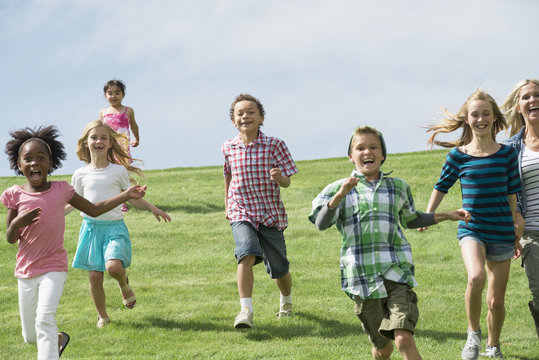 A group of children running across a grass field. 