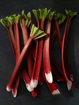 Sticks of fresh rhubarb with long pink stems, and cut leaves. 